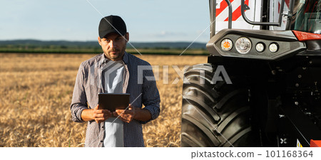 Farmer with digital tablet on a background of combine harvester. 101168364