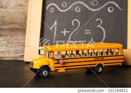 School bus model on black table near chalkboard. Transport for students School bus model on black table near chalkboard. Transport for students 101168652