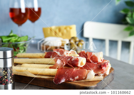 Tasty prosciutto with breadsticks on grey table Tasty prosciutto with breadsticks on grey table 101168662