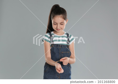 Girl putting sticking plaster onto wrist against light grey background 101168800