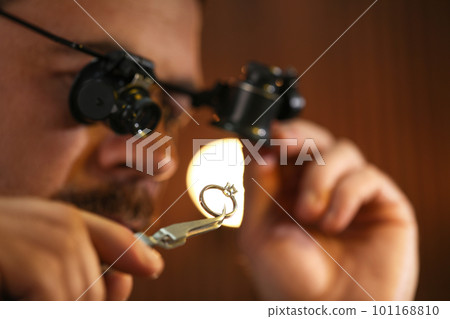 Jeweler working with ring on blurred background, closeup 101168810