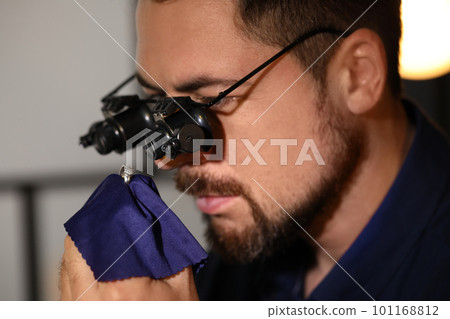 Jeweler working with ring on blurred background, closeup Jeweler working with ring on blurred background, closeup 101168812