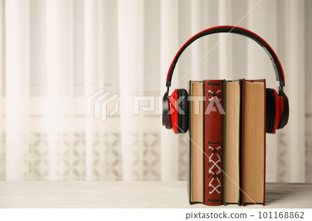 Books and headphones on white wooden table, space for text 101168862