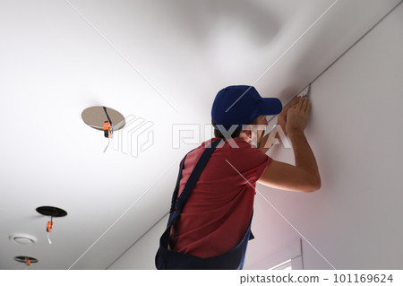 Worker installing stretch ceiling in empty room 101169624