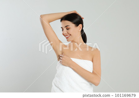 Young woman showing hairless armpit after epilation procedure on light grey background Young woman showing hairless armpit after epilation procedure on light grey background 101169679