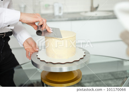 confectioner evens out cake, covers with white chocolate. Home production, business, entrepreneur, hobby. Delicious sweets and pastries. confectioner evens out cake, covers with white chocolate. Home production, business, entrepreneur, hobby. Delicious sweets and pastries. 101170066