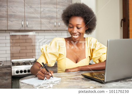 Portrait of beautiful African American freelancer woman, table in kitchen. Work on laptop, indoor. work from home 101170230
