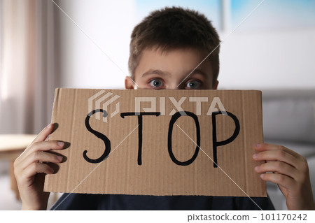Abused little boy with sign STOP indoors. Domestic violence concept 101170242