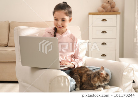 Cute little girl with laptop and cat in armchair at home. First pet Cute little girl with laptop and cat in armchair at home. First pet 101170244