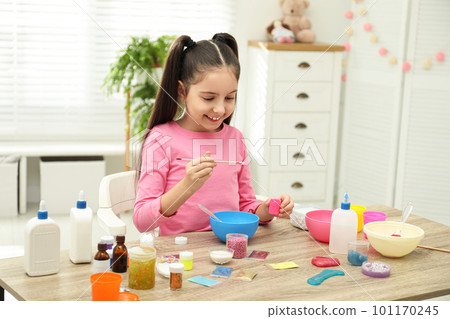 Cute little girl making homemade slime toy at table indoors Cute little girl making homemade slime toy at table indoors 101170245