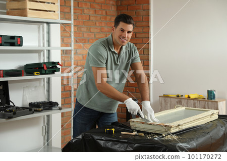 Man repairing old damaged window at table indoors 101170272