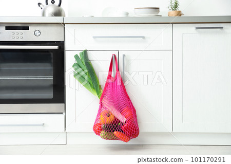 Net bag with vegetables hanging on cabinet door in kitchen Net bag with vegetables hanging on cabinet door in kitchen 101170291