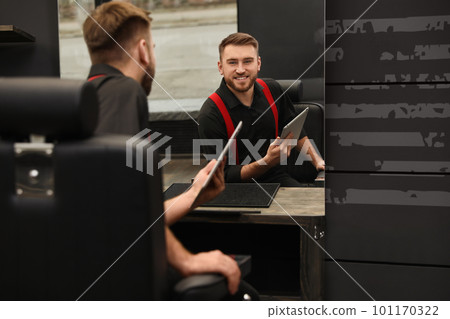 Young business owner with tablet in barber shop 101170322