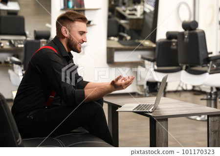 Young business owner working with laptop in barber shop 101170323
