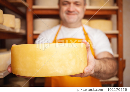 Portrait of cheesemaker in cellar, basement. Home cheese production, business, entrepreneur. Indoors, wooden shelves. 101170356