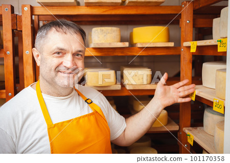 Cheese seller in store, home production, business, entrepreneur. Smiling man, portrait. Businessman, sale of cheese products. Made with love and care. Cheese seller in store, home production, business, entrepreneur. Smiling man, portrait. Businessman, sale of cheese products. Made with love and care. 101170358