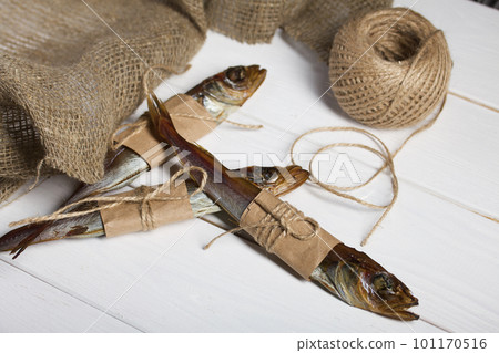 Putassu Cold smoked. The fish is wrapped with a strip of paper. Tied with linen twine. Nearby is a linen cloth and a skein of twine. Close-up. Putassu Cold smoked. The fish is wrapped with a strip of paper. Tied with linen twine. Nearby is a linen cloth and a skein of twine. Close-up. 101170516