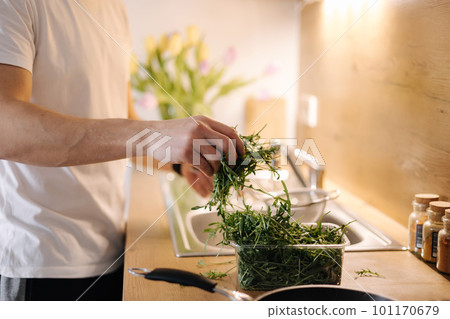 Side view of human hand take a bunch of arugula and rinses with water 101170679