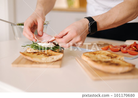 Man put slice of Italian prosciutto on top of bruschetta. Healthy home made food 101170680
