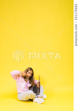 Positive kid sit with laptop read homework wear casual style cloth isolated over yellow background Positive kid sit with laptop read homework wear casual style cloth isolated over yellow background 101170885