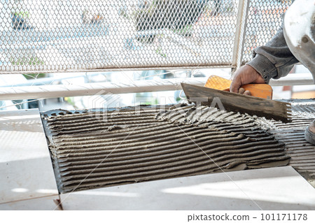 Bricklayer preparing cement on a slab using a notched trowel. I work in a construction. 101171178