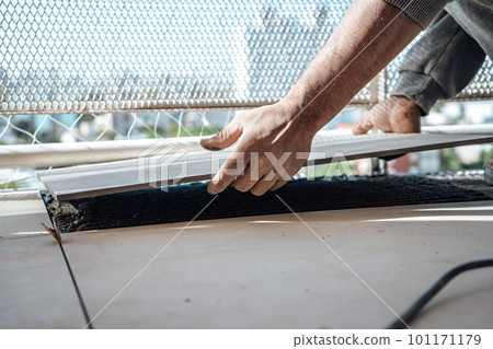 Mason laying a tile in the space prepared in the floor. I work in a construction. 101171179