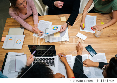Close-up high-angle view of diverse businesswomen, businessmen and office workers working in team conference with project planning document on meeting table. Concept of creative business team. 101171206