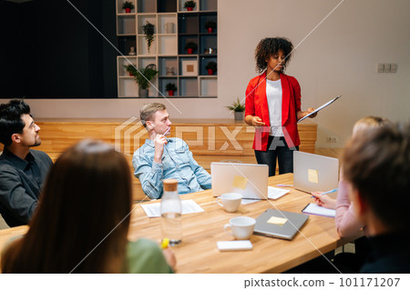 Remote view of diverse business team in boardroom listening to female African American manager making report about project progress. Businesswoman giving presentation during meeting. 101171207