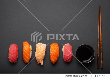 Traditional Japanese sushi top view with soy sauce and chopsticks on dark black minimal background. Sushi with salmon, tuna, shrimp, space for text 101171469