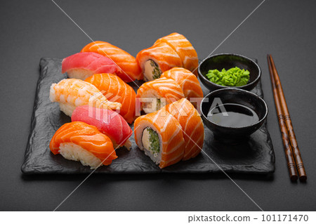 Set of traditional Japanese sushi and rolls angle view with soy sauce and wasabi on dark black rustic slate. Sushi with salmon, tuna, shrimp Set of traditional Japanese sushi and rolls angle view with soy sauce and wasabi on dark black rustic slate. Sushi with salmon, tuna, shrimp 101171470