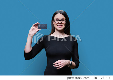 Young woman holding credit card in her hands on blue background 101171995