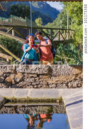 Eco friendly ancient lavoir washhouse. Mixed race mid couple photographing with smartphone. 101173388