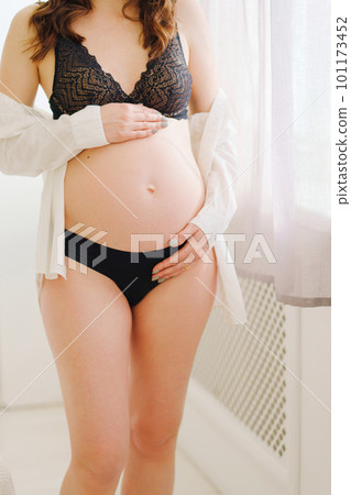 a beautiful pregnant woman in a black underwea and white shirt by the window a beautiful pregnant woman in a black underwea and white shirt by the window 101173452