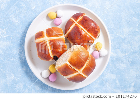 Traditional easter food hot cross buns on white plate with chocolate candy eggs, horizontal, top 101174270