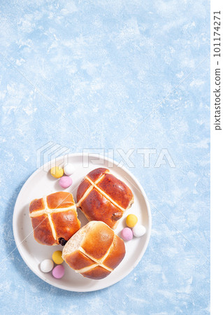 Hot cross buns on white plate with chocolate candy eggs. Traditional easter food, vertical, top view Hot cross buns on white plate with chocolate candy eggs. Traditional easter food, vertical, top view 101174271