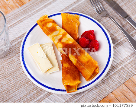 Portion of rolled pancakes with raspberries, honey and pieces of cheese Portion of rolled pancakes with raspberries, honey and pieces of cheese 101177589