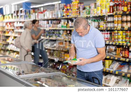 Mature man shopping in supermarket, choosing frozen convenience food 101177607