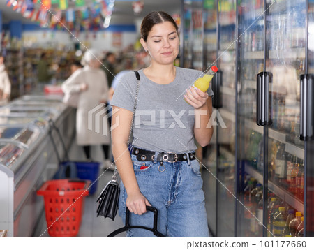 Young girl choosing soft drinks while shopping in supermarket Young girl choosing soft drinks while shopping in supermarket 101177660