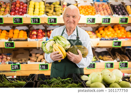 Portrait of contented elderly supermarket employee holding fruit 101177750