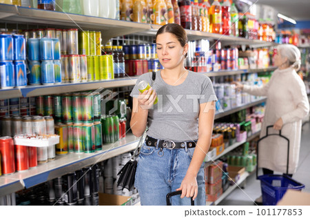Young woman purchaser choosing cool drink in big supermarket Young woman purchaser choosing cool drink in big supermarket 101177853