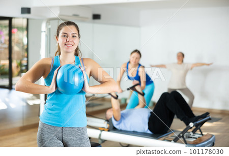 Girl doing chest muscles exercises with pilates ball 101178030