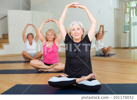 Senior women sitting in lotus pose during group training 101178032