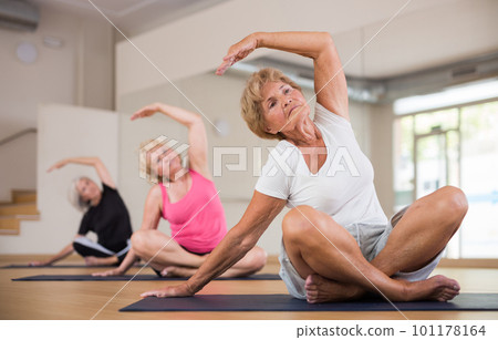 Elderly women practicing yoga trainin the lotus position 101178164
