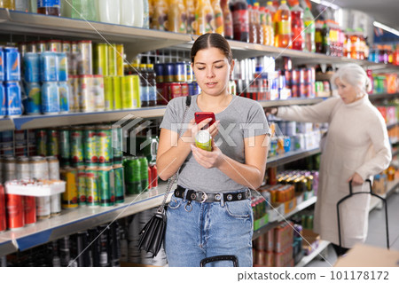 Young girl scanning QR code with phone on tin can of soft drink Young girl scanning QR code with phone on tin can of soft drink 101178172