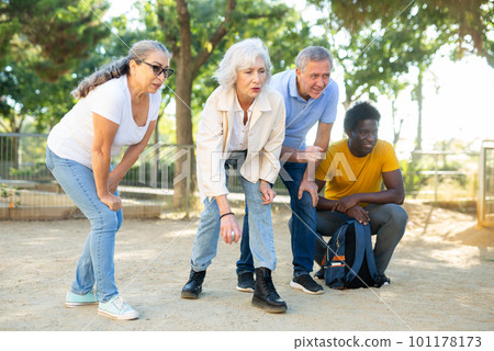 Carefree multiracial friends throwing metal balls on a sandy background in the park Carefree multiracial friends throwing metal balls on a sandy background in the park 101178173