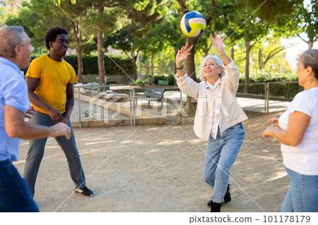 Two mature couples playing volleyball in summer park Two mature couples playing volleyball in summer park 101178179