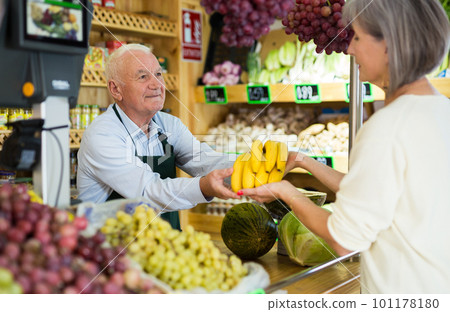 Old man cashier serving customer in greengrocer Old man cashier serving customer in greengrocer 101178180