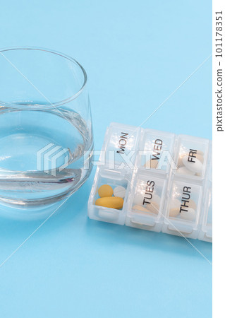 Weekly pill organizer with sunday open compartment and glass of water Weekly pill organizer with sunday open compartment and glass of water 101178351