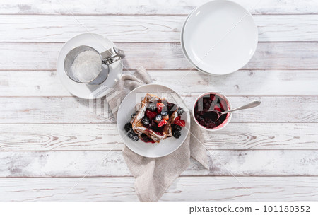 Stack of freshly made french toast garnished with mix berry compote and powder sugar. Stack of freshly made french toast garnished with mix berry compote and powder sugar. 101180352