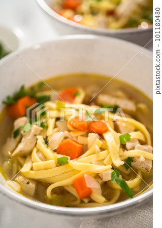 Serving chicken noodle soup with kluski noodles in white ceramic soup bowls. 101180480